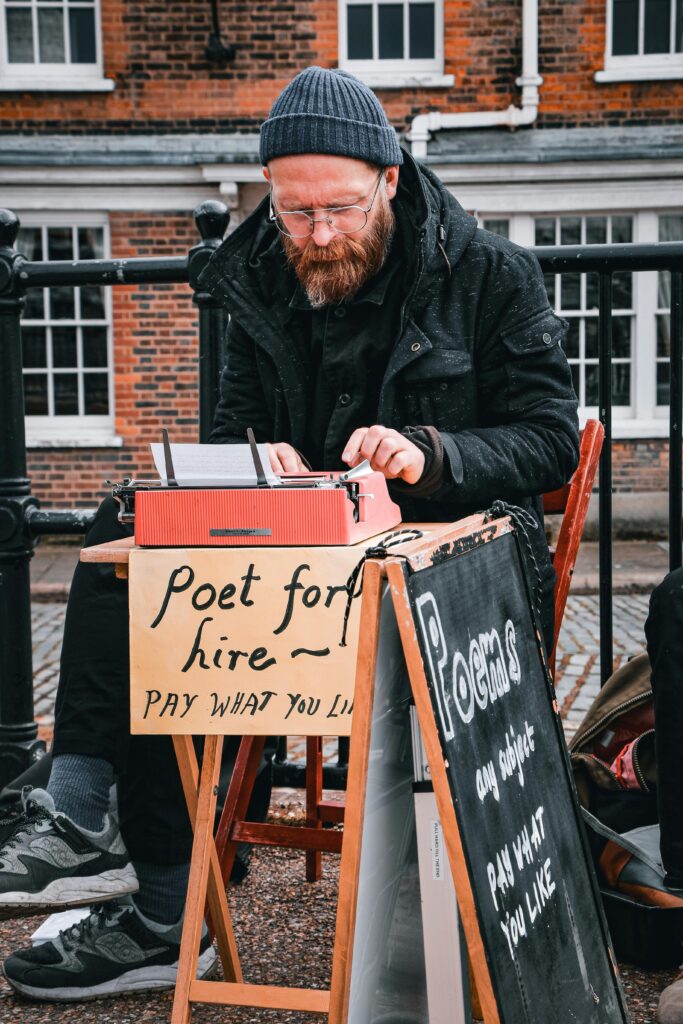 Man typing on a typewriter offering poems for hire on a London street corner.