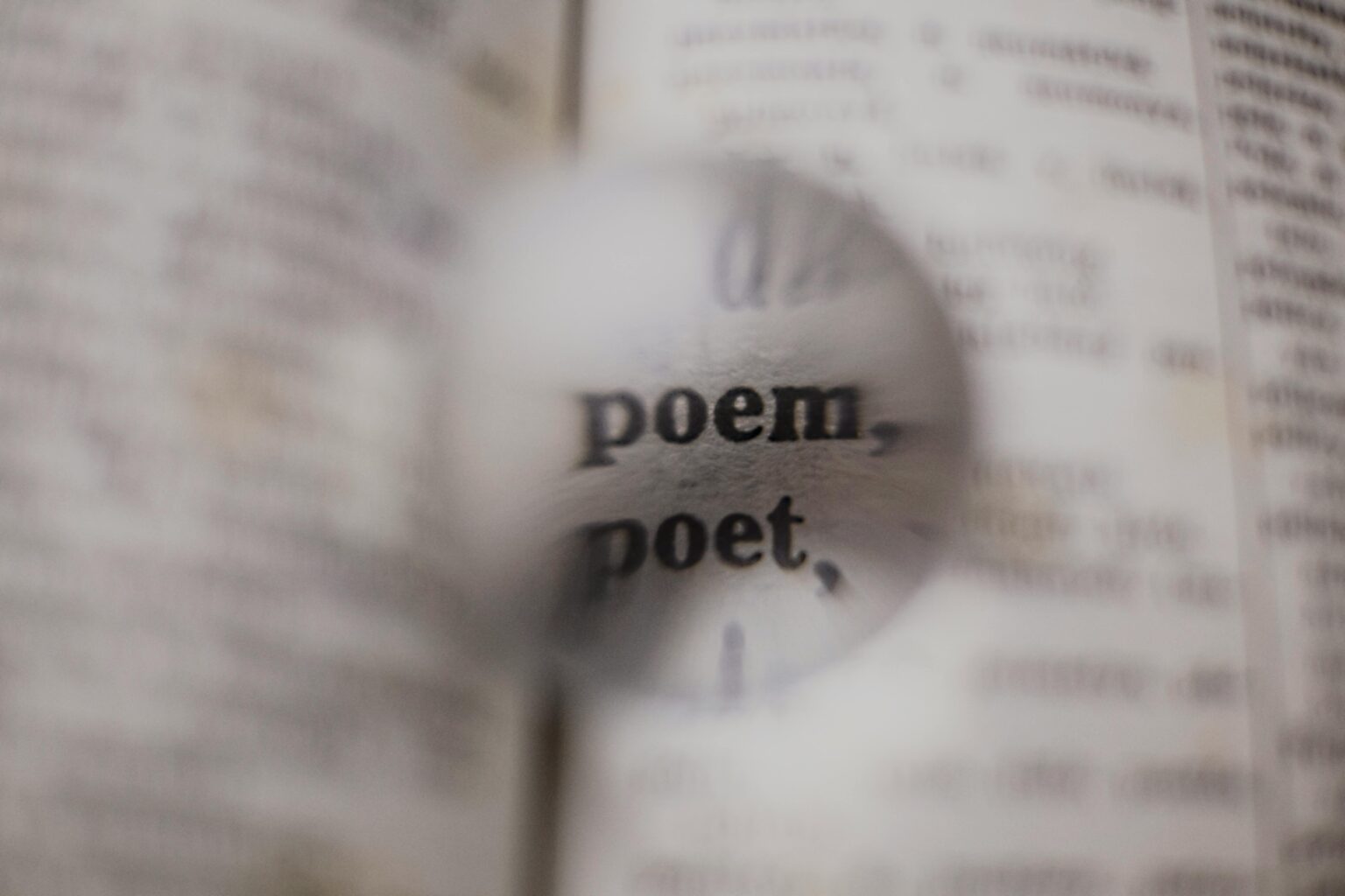 Close-up of words 'poem' and 'poet' magnified in a dictionary